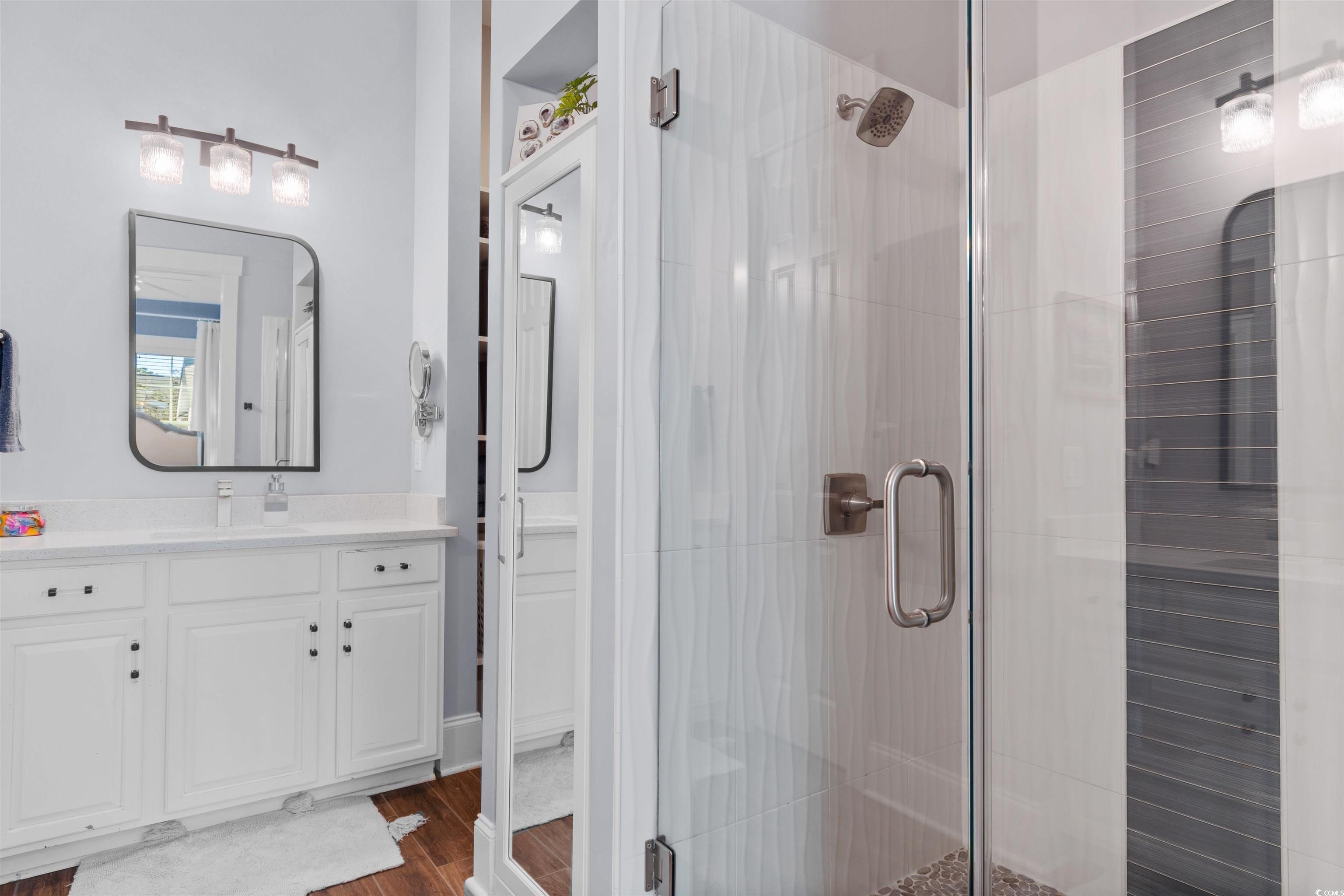 3448 Baldwin Lane Myrtle Beach, SC 29577 - Photo 14 of 30 Bathroom featuring dark wood finished floors, two vanities, and a shower stall