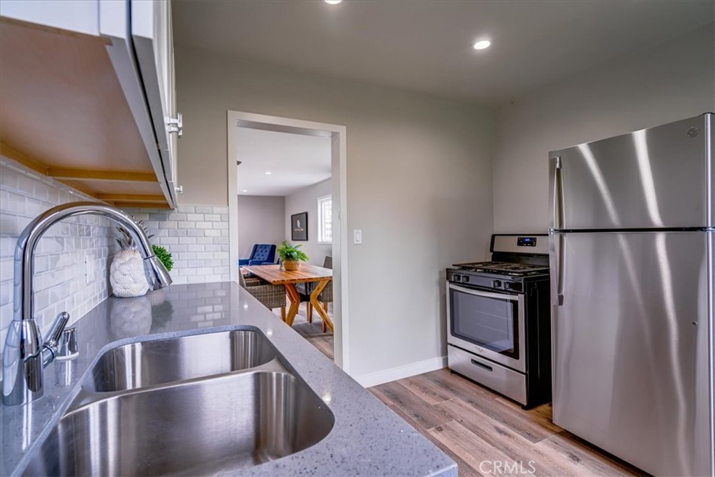 323 Culver Boulevard Playa del Rey, CA 90293 - Photo 19 of 58 a kitchen with stainless steel appliances granite countertop a refrigerator a stove and a sink with wooden floor