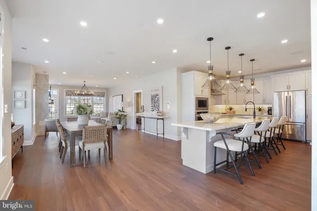 an open kitchen with kitchen island a dining table chairs and wooden floor