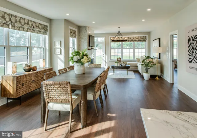 a dining room with wooden floor and large windows