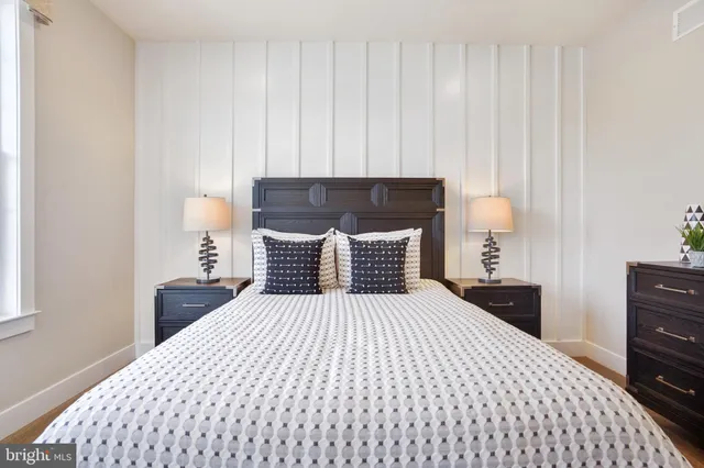 a bedroom with a bed and a lamp on dresser