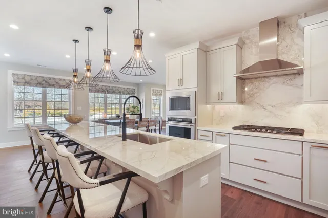 a kitchen with stainless steel appliances kitchen island a table chairs in it and white cabinets