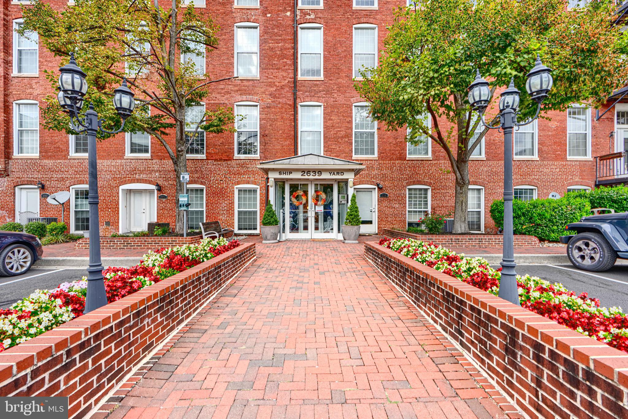 a front view of a multi story residential apartment building with yard and bench