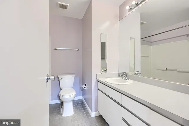 a bathroom with a granite countertop sink a toilet and a large mirror