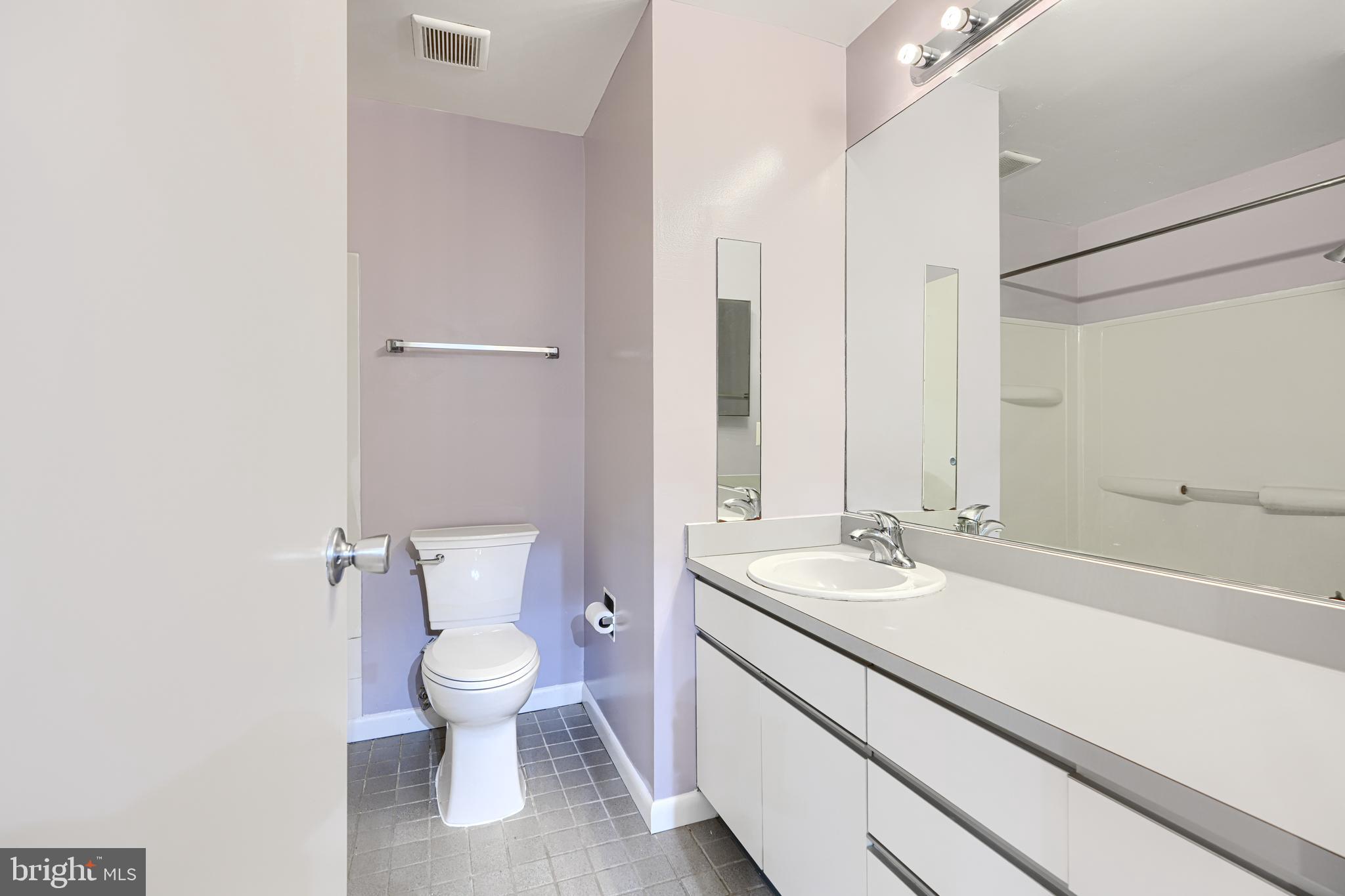2639 Boston Street, Unit 305 Baltimore, MD 21224 - Photo 18 of 21 a bathroom with a granite countertop sink a toilet and a large mirror