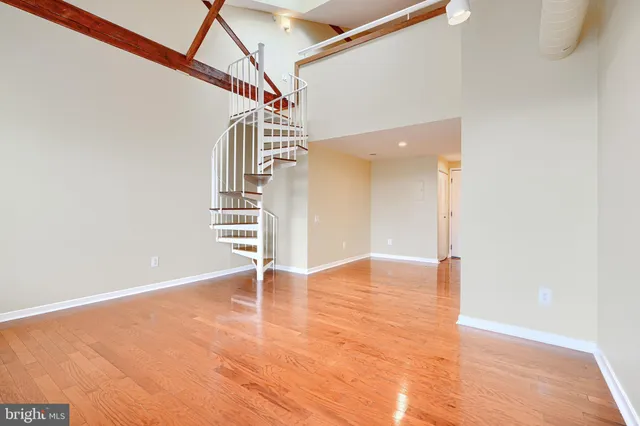 a view of an empty room with stairs and wooden floor