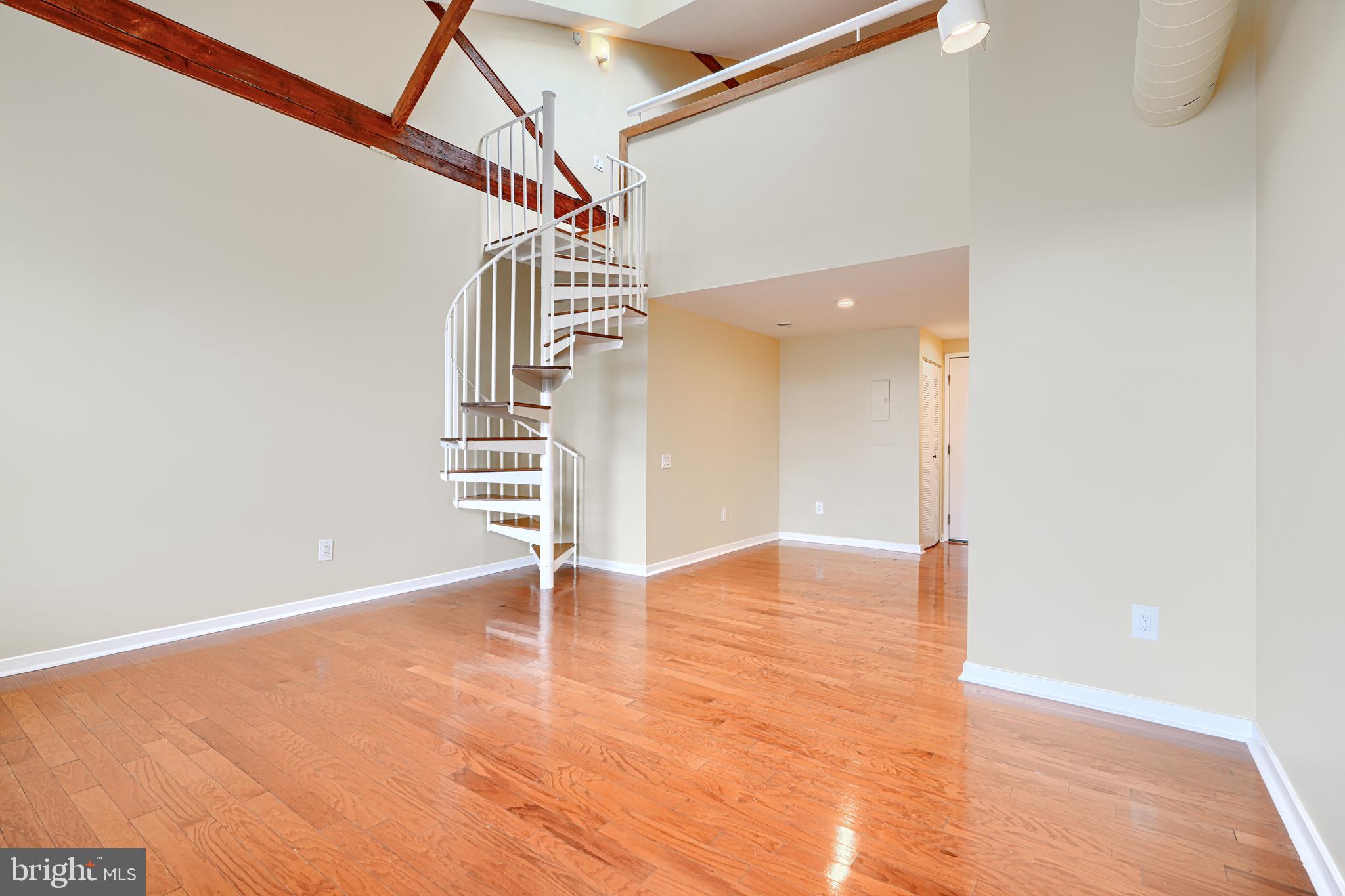 2639 Boston Street, Unit 305 Baltimore, MD 21224 - Photo 8 of 21 a view of an empty room with stairs and wooden floor