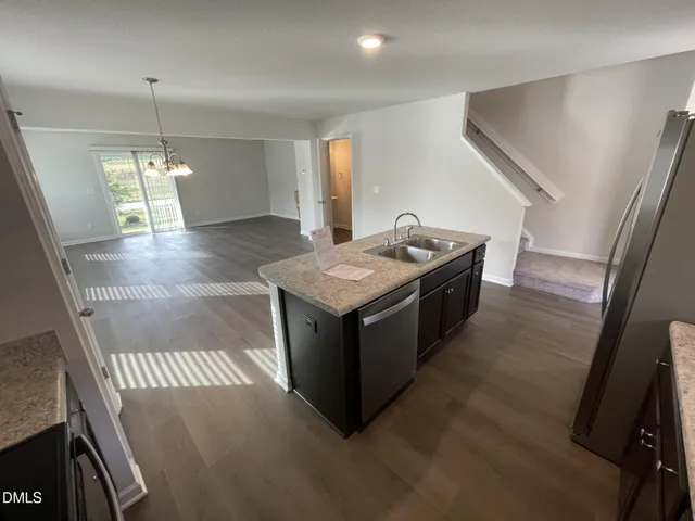 a view of a living room with kitchen island stainless steel appliances wooden floor and living room view