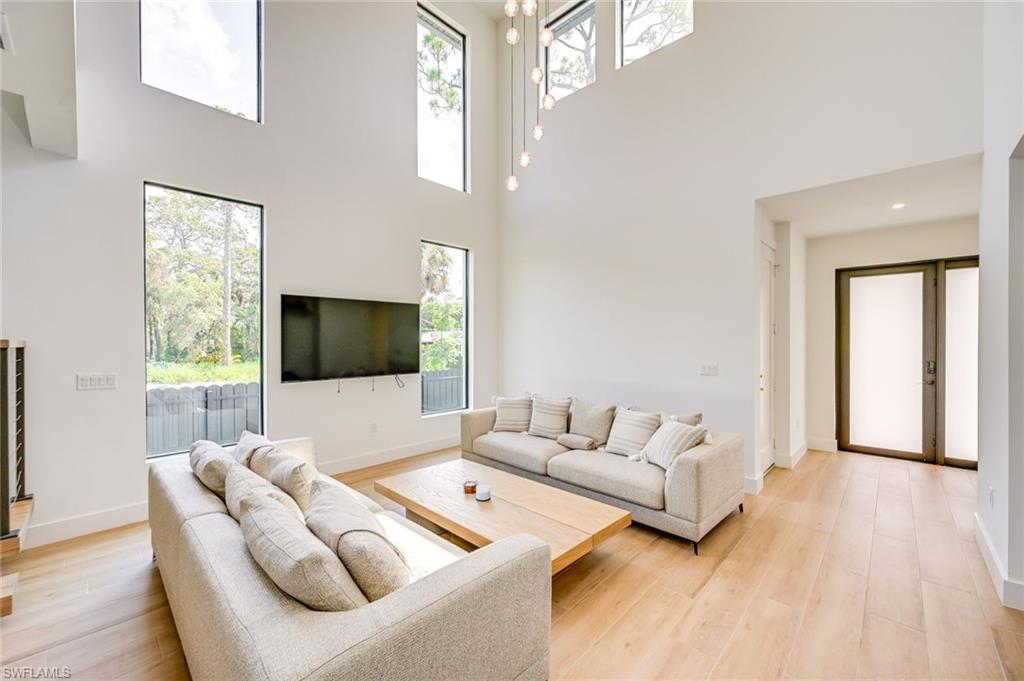 3384 Canal Street Naples, FL 34112 - Photo 5 of 34 Living room featuring healthy amount of natural light, a high ceiling, and light wood-style flooring