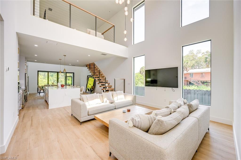 3384 Canal Street Naples, FL 34112 - Photo 6 of 34 Living room featuring stairway, light wood-style floors, a high ceiling, and a chandelier