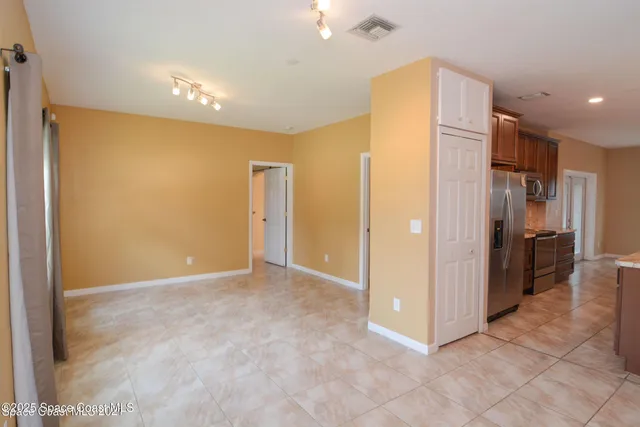 a view of an empty room with kitchen and a window
