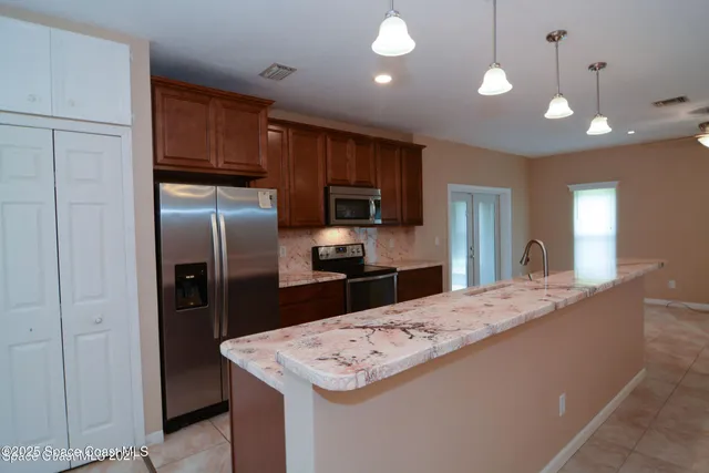 a kitchen with kitchen island a refrigerator and a sink