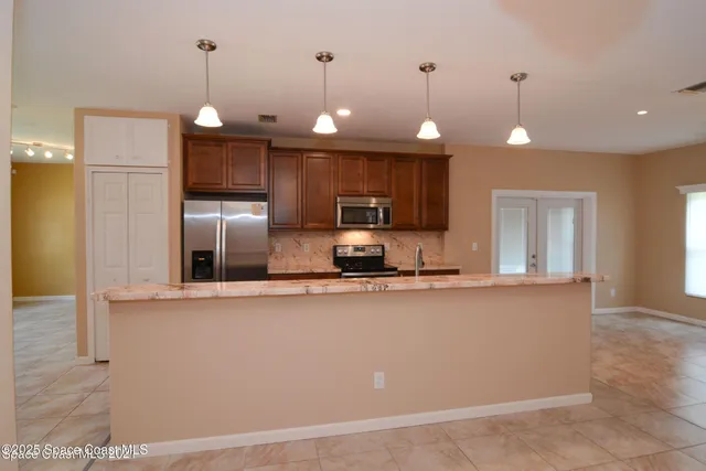a large kitchen with a refrigerator a sink and a wooden floor