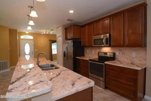 a kitchen with stainless steel appliances wooden cabinets a stove a sink and a microwave