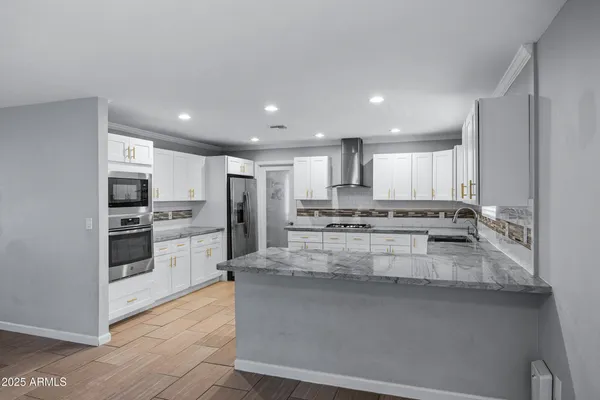 a kitchen with stainless steel appliances granite countertop a refrigerator and a stove top oven