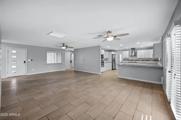 a view of empty room with wooden floor and kitchen view