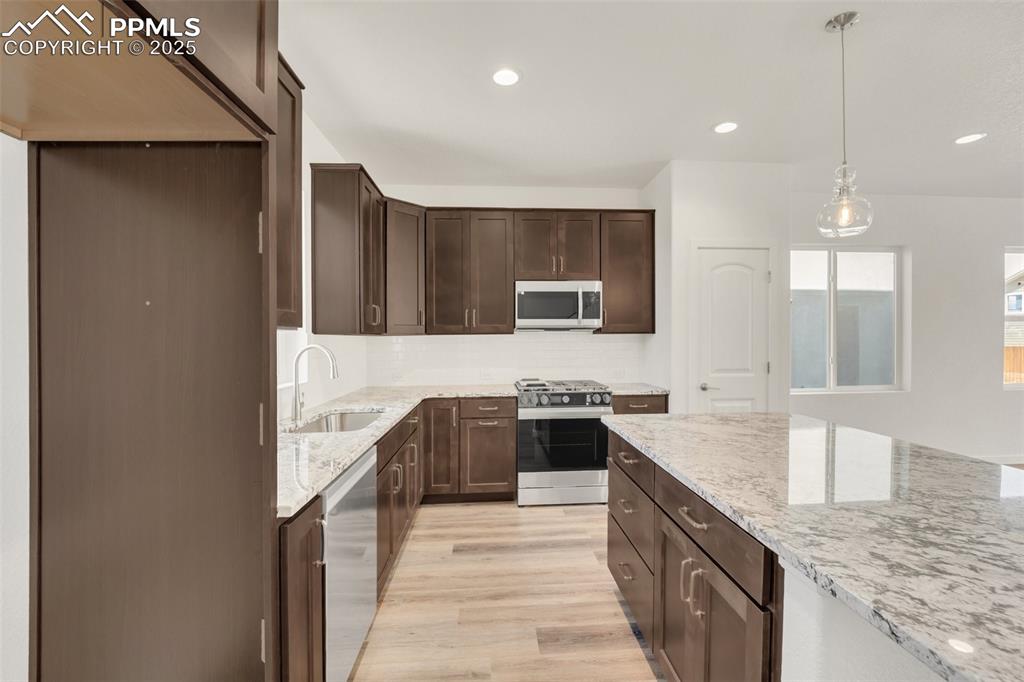 8156 Manor House Way Colorado Springs, CO 80908 - Photo 11 of 35 a kitchen with stainless steel appliances granite countertop a sink stove and refrigerator