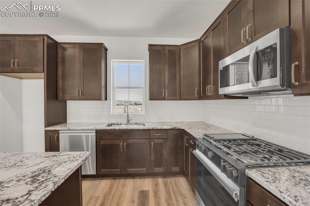 8156 Manor House Way Colorado Springs, CO 80908 - Photo 12 of 35 a kitchen with stainless steel appliances granite countertop a stove a sink dishwasher and a refrigerator