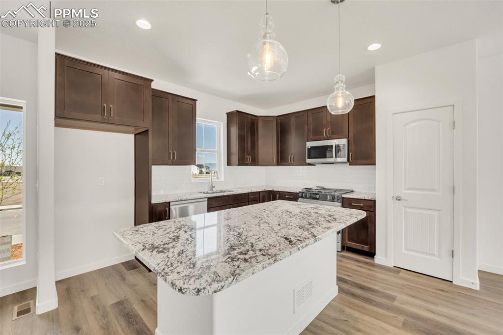 8156 Manor House Way Colorado Springs, CO 80908 - Photo 10 of 35 a kitchen with kitchen island granite countertop a sink and a refrigerator