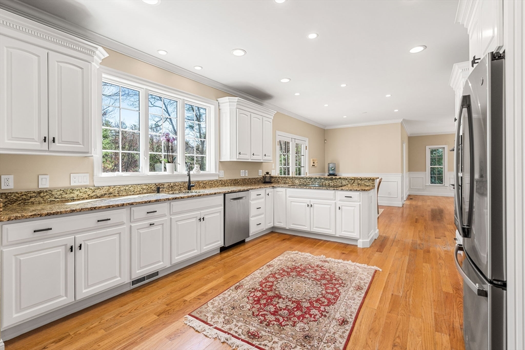 10 Sawyer Lane Middleton, MA 01949 - Photo 17 of 46 a large kitchen with granite countertop a sink dishwasher a stove and white cabinets with wooden floor