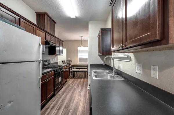 a kitchen with stainless steel appliances granite countertop a refrigerator a stove and a wooden floor