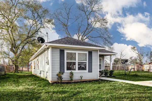 a view of a yard in front of a house with a large tree