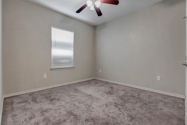 an empty room with a chandelier fan and windows
