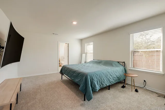 a spacious bedroom with a bed and a flat screen tv