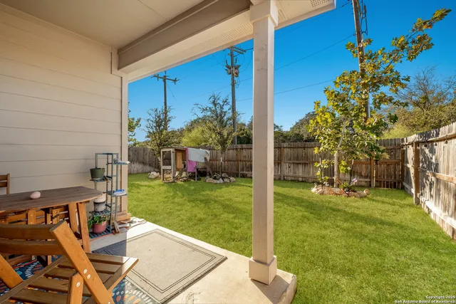 a view of a backyard with couches plants and large trees