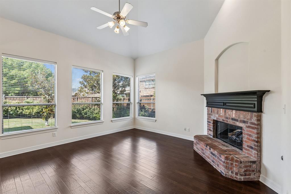 960 Remuda Road Frisco, TX 75033 - Photo 27 of 39 Vaulted ceiling with a ceiling fan, wood-finish flooring, brick fireplace with a dark mantel, multiple windows, and an arched wall niche