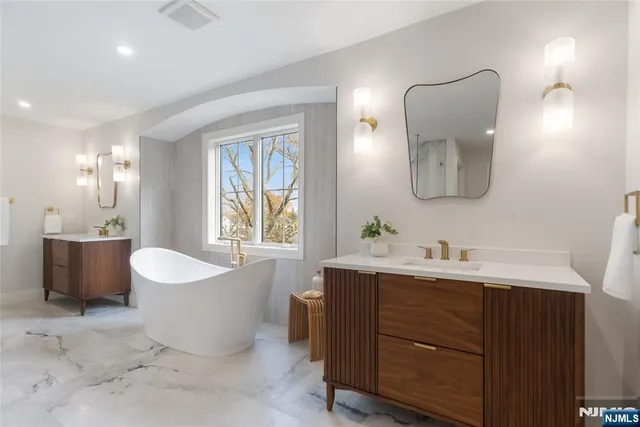 a bathroom with a double vanity sink mirror and bathtub
