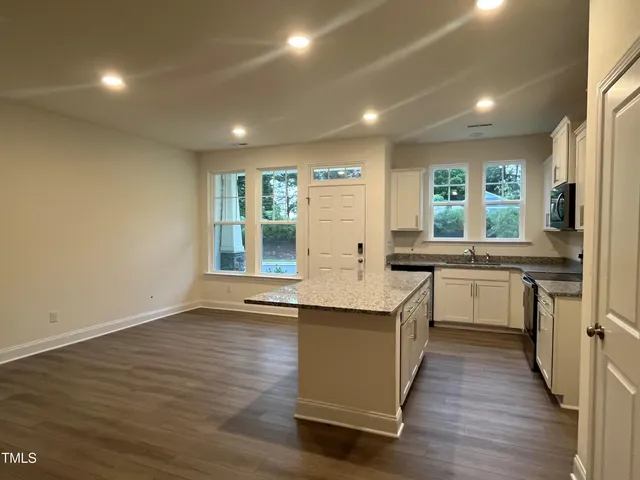 a kitchen with granite countertop a sink a stove a microwave and cabinets