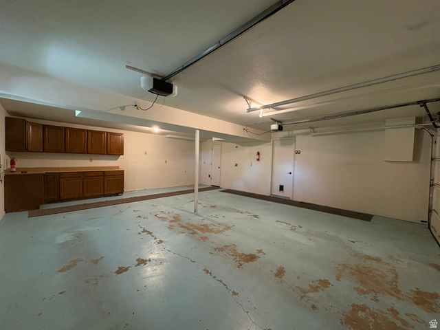 595 Meadowlark Road Orem, UT 84097 - Photo 65 of 87 Spacious garage featuring extensive built-in cabinetry and countertops, a durable painted concrete floor, overhead lighting, and an automatic garage door opener