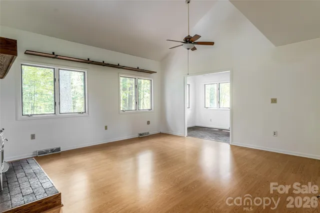 a view of an empty room with a window and wooden floor