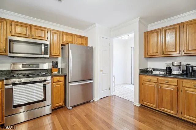 a kitchen with granite countertop wooden floors stainless steel appliances and a window