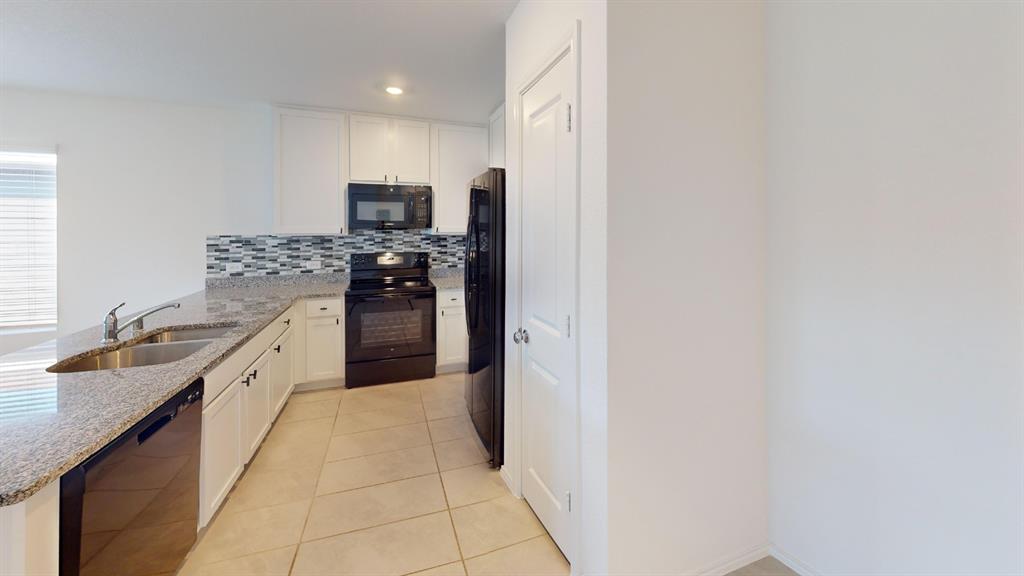 403 Ashbrook Way Princeton, TX 75407 - Photo 6 of 23 Kitchen featuring granite-style countertops, white cabinetry, integrated stainless steel sink, black electric range with an overhead microwave, and a black refrigerator