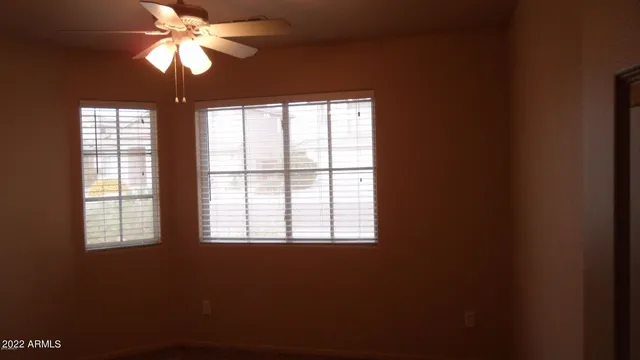 an empty room with a window and a ceiling fan