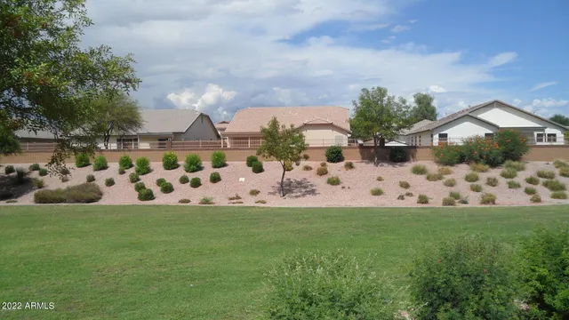 a view of white house with a big yard and large trees