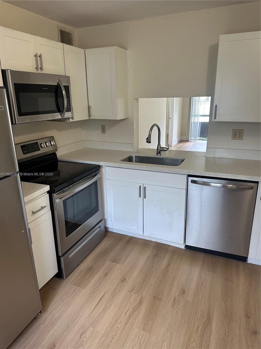 130 Northwest 60th Avenue, Unit 12 Margate, FL 33063 - Photo 1 of 16 a kitchen with granite countertop wooden cabinets stainless steel appliances and a sink