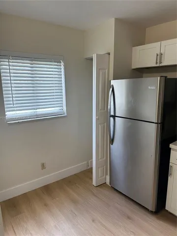 a view of a refrigerator in kitchen and an empty room
