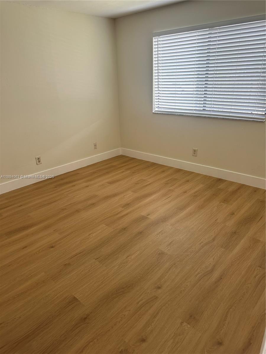 130 Northwest 60th Avenue, Unit 12 Margate, FL 33063 - Photo 6 of 16 a view of an empty room with wooden floor and a window
