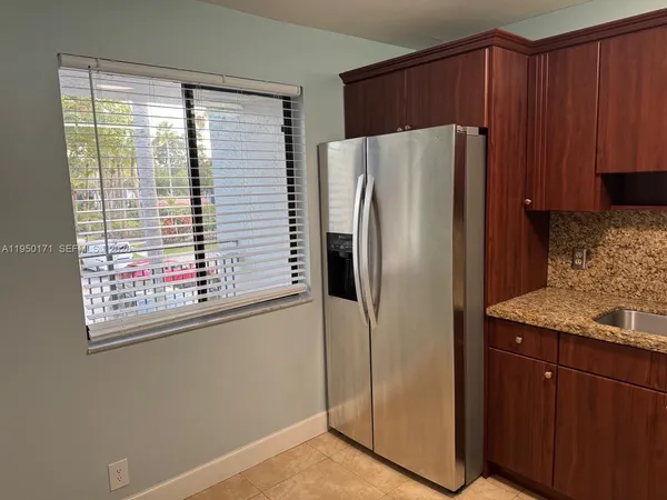 a metallic refrigerator sitting inside of a kitchen