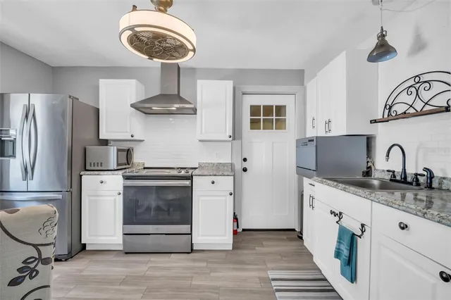 a kitchen with stainless steel appliances granite countertop a stove a refrigerator and a sink with wooden floor