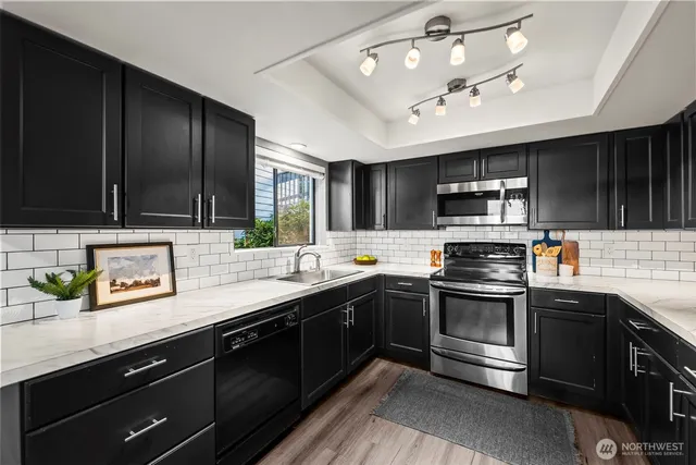 a kitchen with stainless steel appliances granite countertop a sink dishwasher stove top oven and wooden cabinets