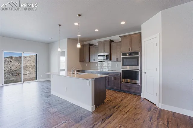 a large kitchen with stainless steel appliances granite countertop a large counter top a sink and a stove