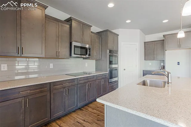 a kitchen with kitchen island granite countertop a sink a stove and cabinets