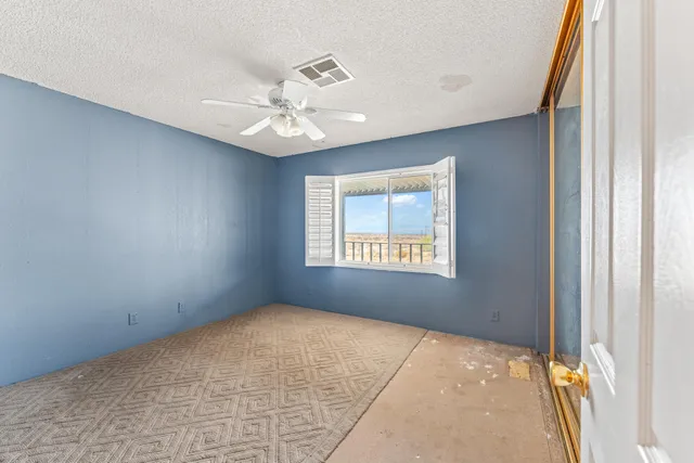 an empty room with windows and fan