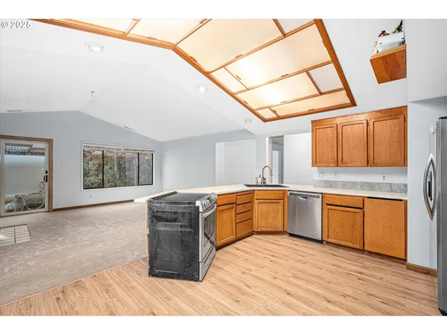 a kitchen with stainless steel appliances granite countertop a stove a sink and a refrigerator with wooden floor