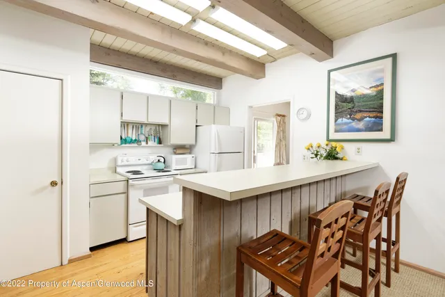 a kitchen with stainless steel appliances kitchen island a table chairs and a refrigerator
