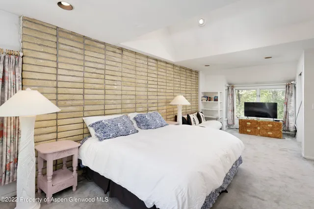 a spacious bedroom with a bed and a flat screen tv